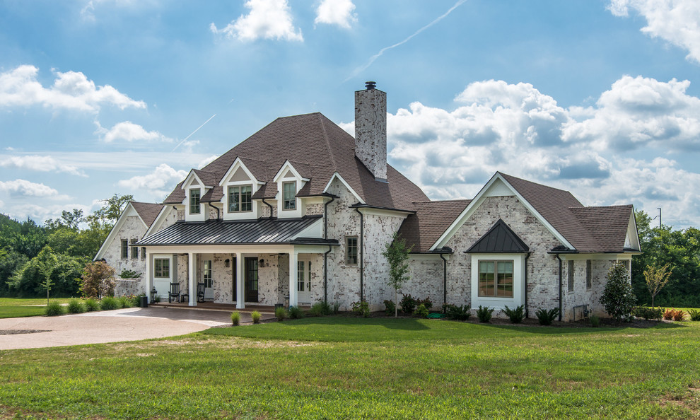 This is an example of a large country two-storey brick white house exterior in Nashville with a shingle roof and a hip roof.