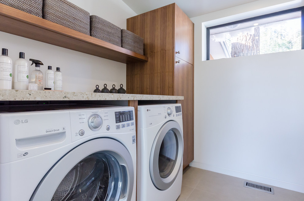 Photo of a mid-sized contemporary galley dedicated laundry room in San Francisco with an undermount sink, flat-panel cabinets, medium wood cabinets, granite benchtops, white walls, travertine floors, a side-by-side washer and dryer and beige floor.