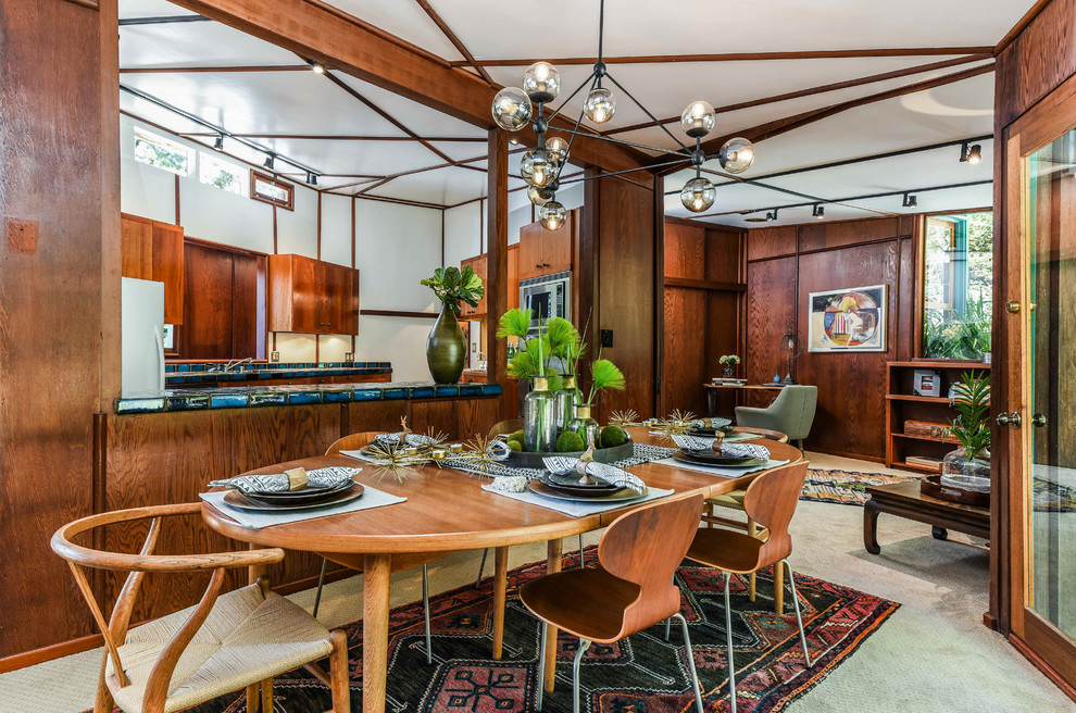 This is an example of a large midcentury separate dining room in San Francisco with brown walls, carpet, no fireplace and grey floor.