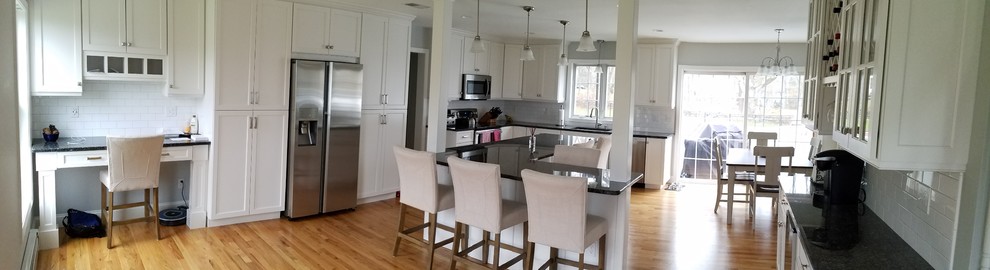 Inspiration for a large transitional l-shaped light wood floor and brown floor eat-in kitchen remodel with an undermount sink, shaker cabinets, white cabinets, granite countertops, white backsplash, subway tile backsplash, stainless steel appliances and an island