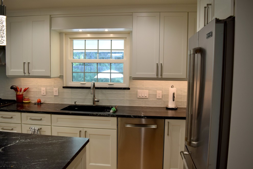 Photo of a contemporary l-shaped eat-in kitchen in Denver with an undermount sink, flat-panel cabinets, white cabinets, granite benchtops, white splashback, glass tile splashback, stainless steel appliances, medium hardwood floors and with island.