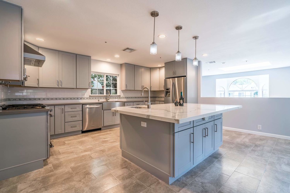 Eat-in kitchen - mid-sized contemporary u-shaped porcelain tile and gray floor eat-in kitchen idea in Orange County with a farmhouse sink, recessed-panel cabinets, gray cabinets, quartz countertops, white backsplash, subway tile backsplash, stainless steel appliances, an island and white countertops