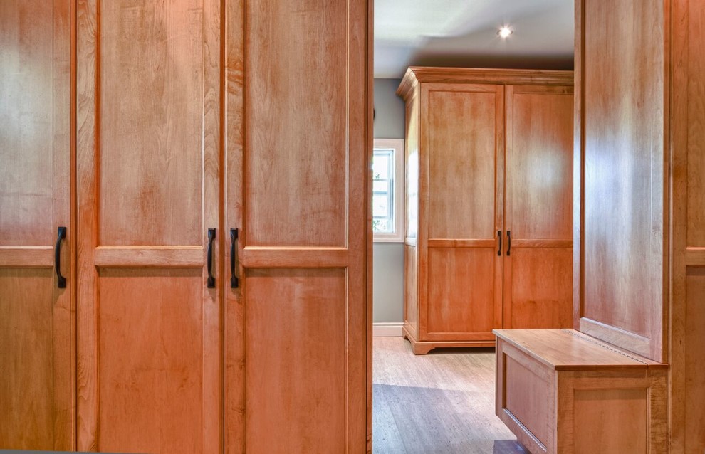 Large transitional gender-neutral walk-in wardrobe in Toronto with shaker cabinets, medium wood cabinets and linoleum floors.