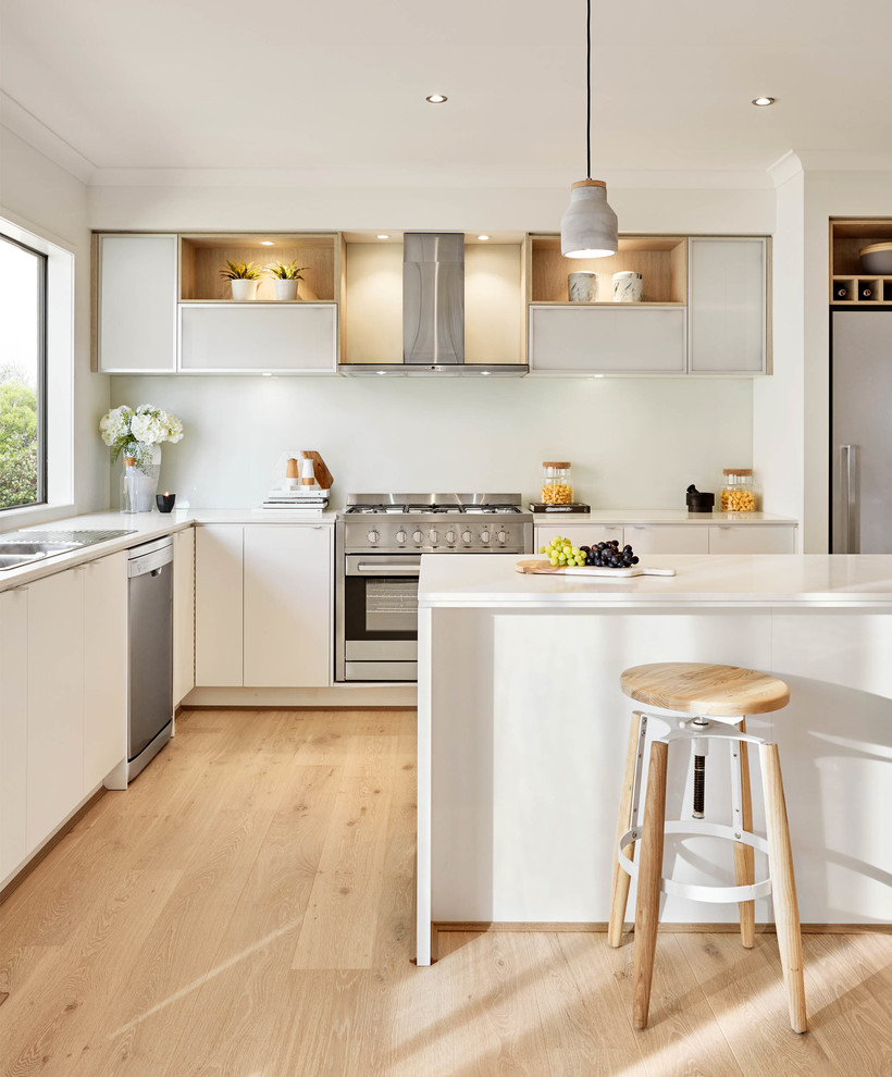 Inspiration for a contemporary l-shaped kitchen in Melbourne with a double-bowl sink, flat-panel cabinets, white cabinets, stainless steel appliances, light hardwood floors and with island.
