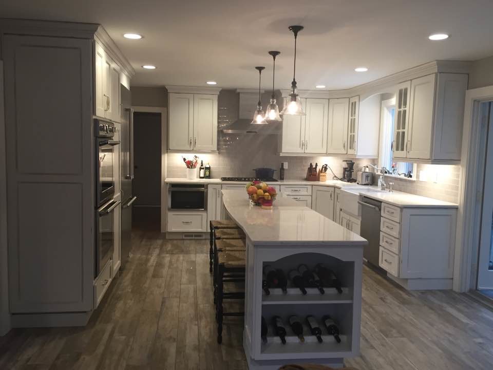 Inspiration for a large country u-shaped open plan kitchen in Boston with a farmhouse sink, recessed-panel cabinets, white cabinets, quartz benchtops, grey splashback, subway tile splashback, stainless steel appliances, porcelain floors and with island.
