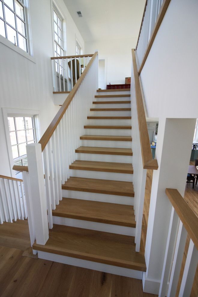 This is an example of a medium sized farmhouse wood u-shaped wood railing staircase in DC Metro with wood risers and tongue and groove walls.