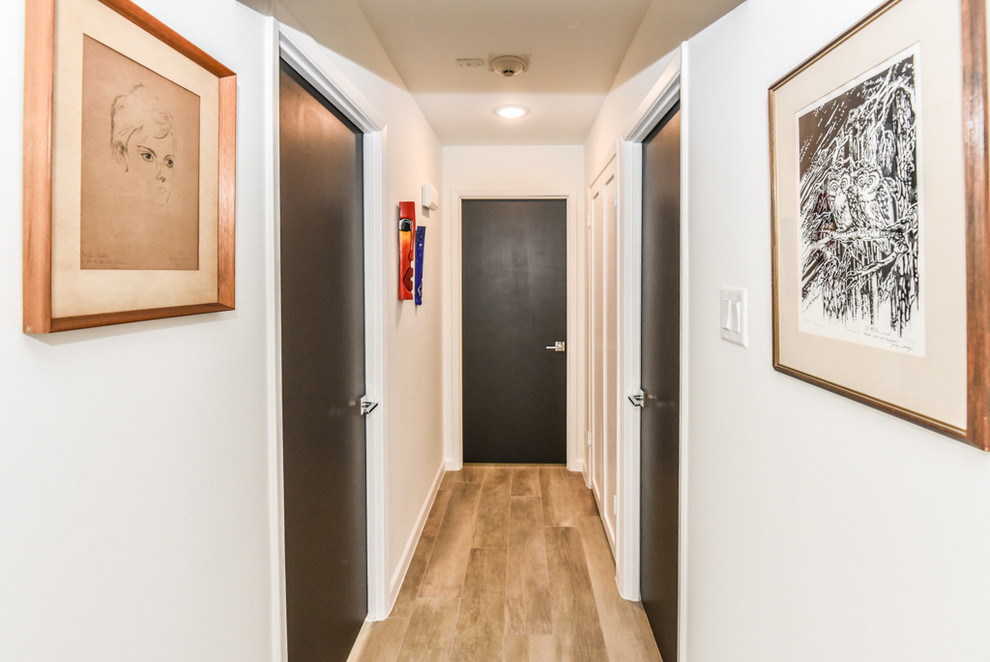 Design ideas for a mid-sized midcentury hallway in Houston with white walls, porcelain floors and beige floor.