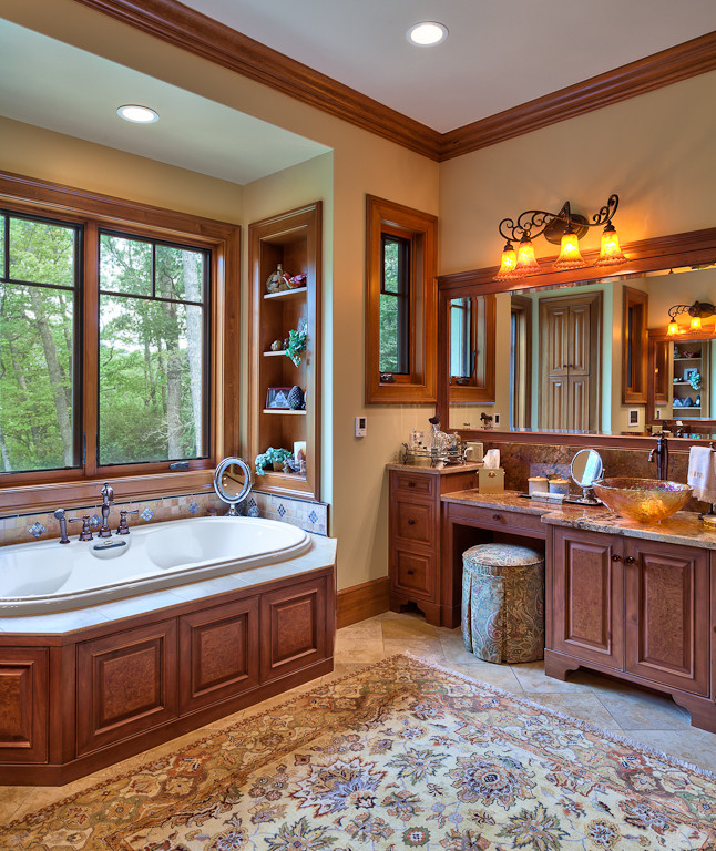 Photo of a large traditional master bathroom in Other with raised-panel cabinets, brown cabinets, an alcove tub, beige walls, slate floors, a vessel sink, marble benchtops, beige floor, beige benchtops, a single vanity and a built-in vanity.