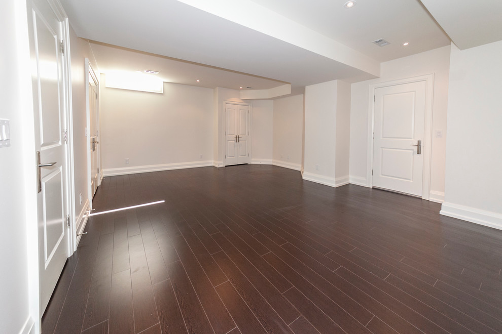 Expansive transitional guest bedroom in Toronto with white walls and laminate floors.