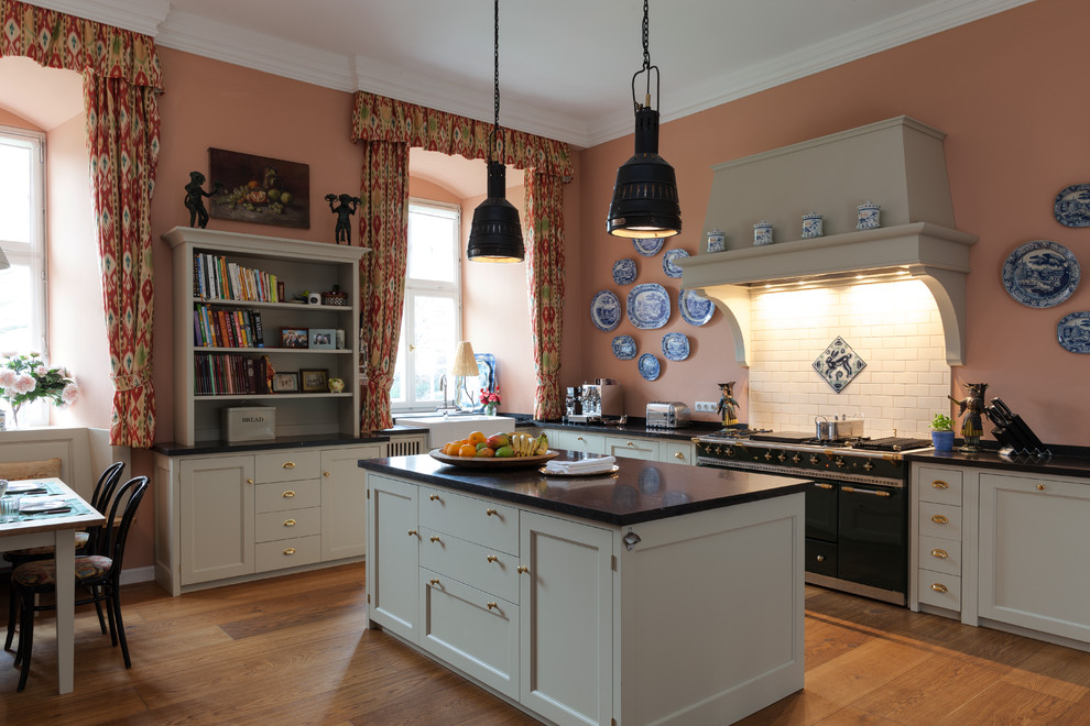 Inspiration for a large country l-shaped open plan kitchen in Cologne with a farmhouse sink, shaker cabinets, beige cabinets, granite benchtops, pink splashback, ceramic splashback, coloured appliances, dark hardwood floors and with island.