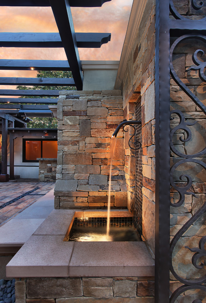 Design ideas for a mid-sized mediterranean courtyard patio in Orange County with a water feature, natural stone pavers and a gazebo/cabana.