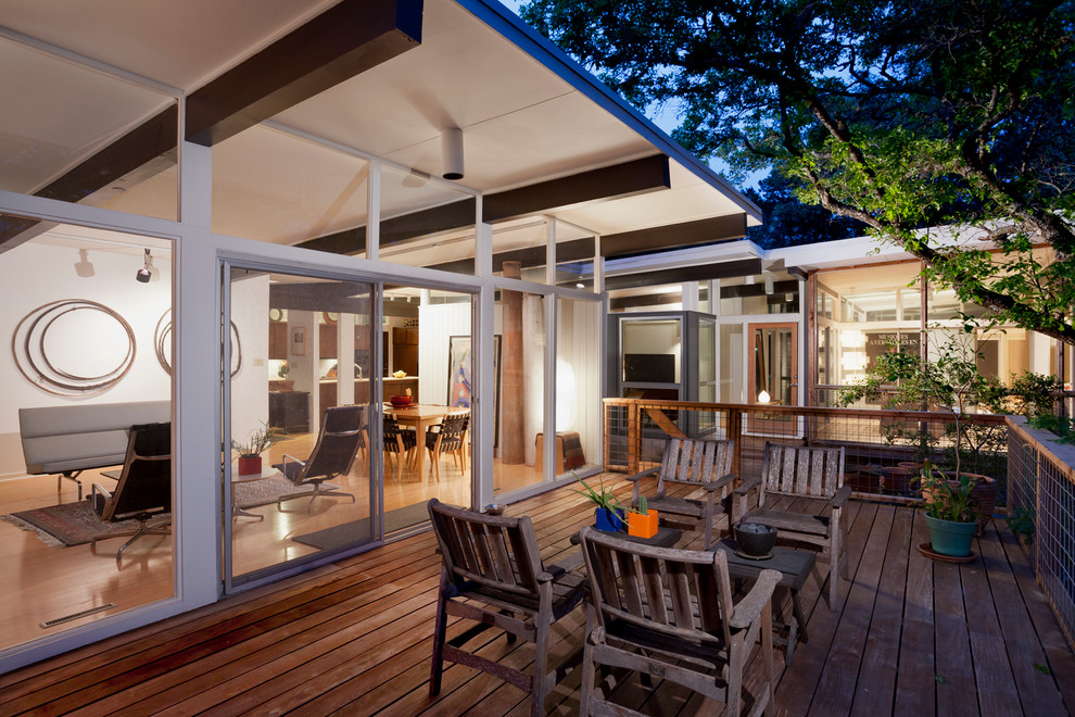 This is an example of a midcentury backyard deck in Austin with a roof extension.