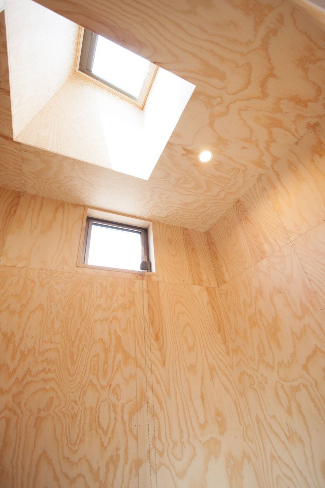 Kleines Maritimes Ankleidezimmer mit Einbauschrank, Porzellan-Bodenfliesen, beigem Boden, freigelegten Dachbalken und hellen Holzschränken in Sonstige