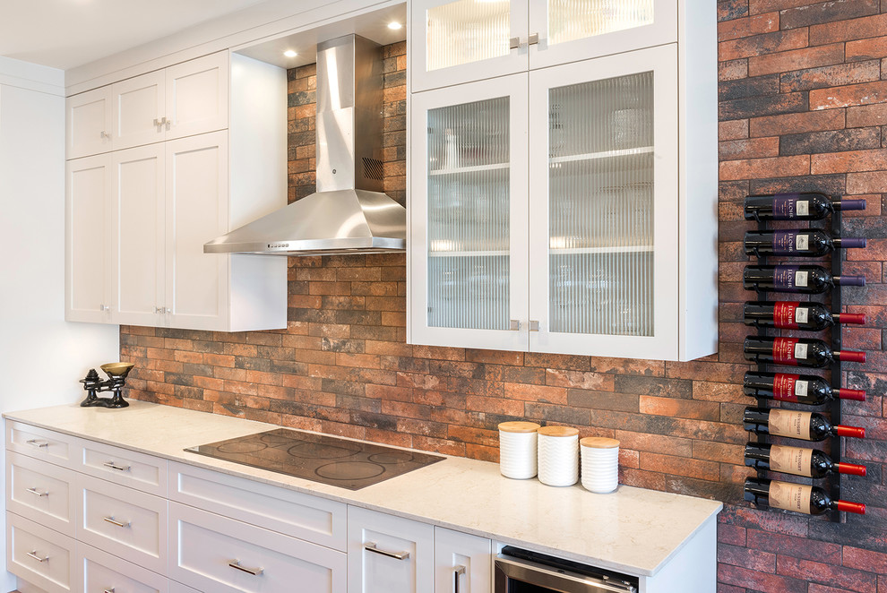 Mid-sized transitional eat-in kitchen in Vancouver with a farmhouse sink, shaker cabinets, white cabinets, quartz benchtops, brown splashback, brick splashback, stainless steel appliances, vinyl floors, with island, beige floor and beige benchtop.