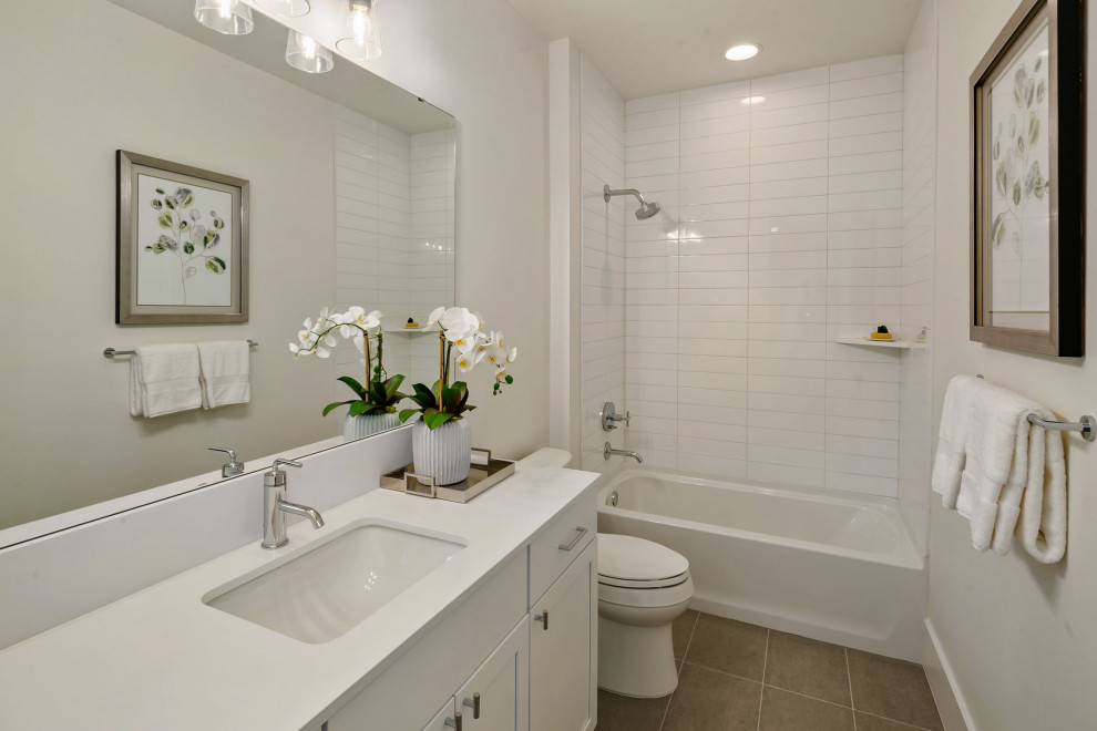 Medium sized farmhouse bathroom in Seattle with recessed-panel cabinets, white cabinets, a shower/bath combination, a one-piece toilet, white walls, a submerged sink, engineered stone worktops, grey floors, white worktops, a single sink, a built in vanity unit, white tiles, metro tiles, cement flooring and an open shower.