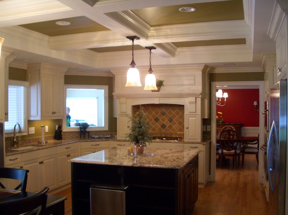 Eat-in kitchen - large transitional u-shaped medium tone wood floor eat-in kitchen idea with an undermount sink, raised-panel cabinets, white cabinets, granite countertops, beige backsplash, stone tile backsplash, stainless steel appliances and an island