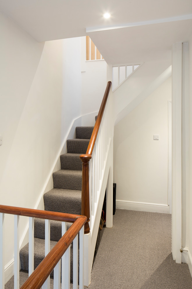 This is an example of a small contemporary hallway in Sussex with white walls, carpet and beige floor.