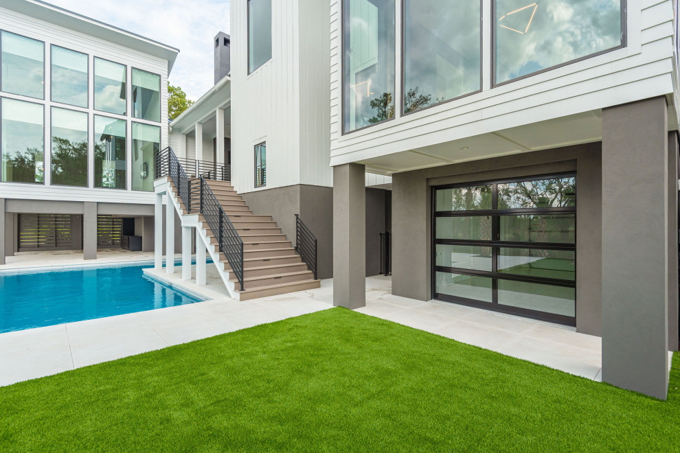 This is an example of a large modern backyard l-shaped pool in Charleston with with privacy feature and concrete pavers.