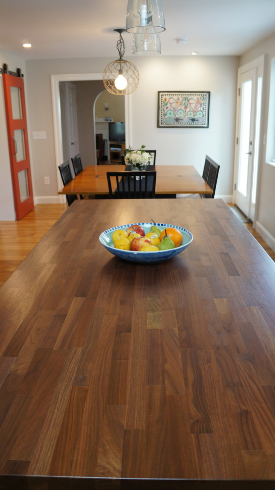 Example of a mid-sized transitional l-shaped medium tone wood floor and brown floor open concept kitchen design in Boston with a single-bowl sink, shaker cabinets, white cabinets, granite countertops, white backsplash, window backsplash, stainless steel appliances, an island and black countertops