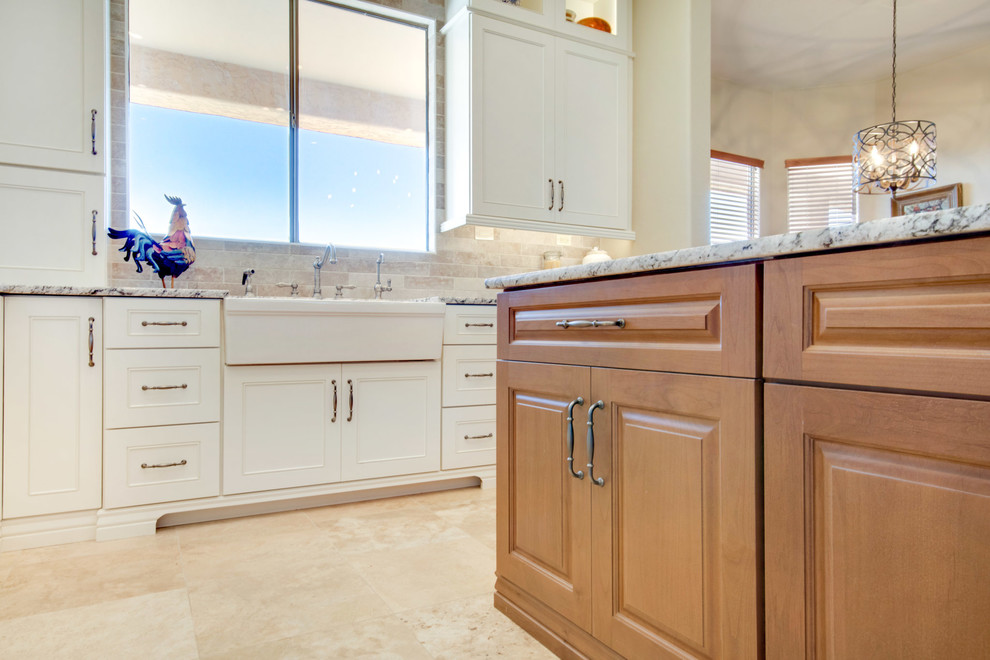 Open concept kitchen - large transitional u-shaped travertine floor and beige floor open concept kitchen idea in Phoenix with a farmhouse sink, recessed-panel cabinets, white cabinets, granite countertops, gray backsplash, porcelain backsplash, stainless steel appliances, an island and multicolored countertops