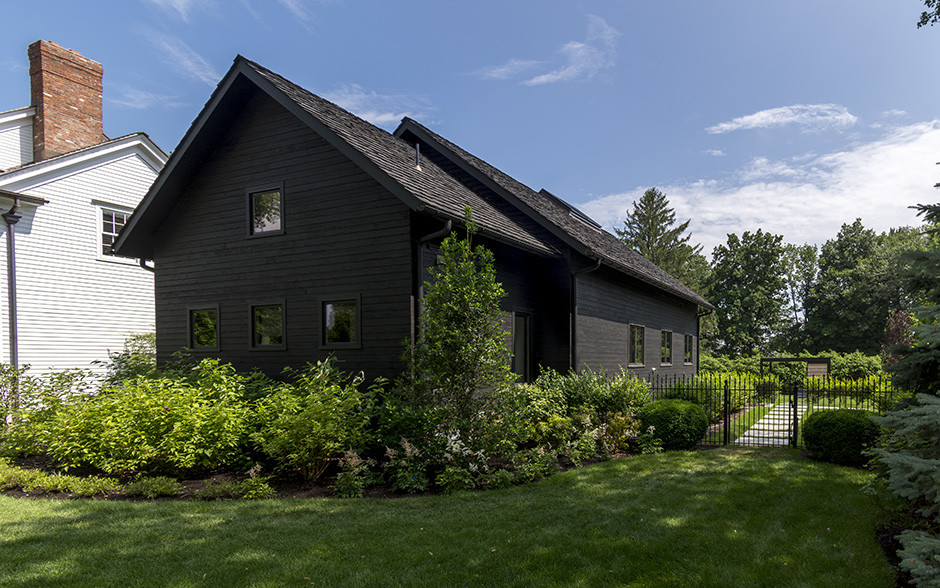 Photo of a mid-sized traditional two-storey black house exterior in Other with wood siding.