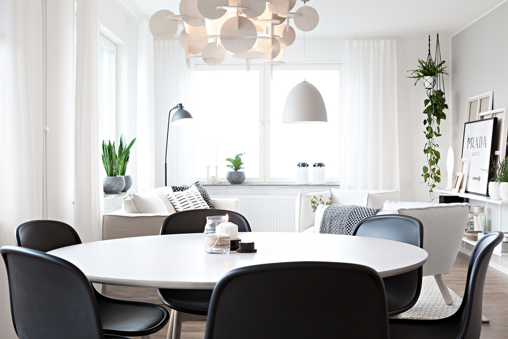 Scandinavian kitchen/dining combo in Gothenburg with white walls, light hardwood floors and brown floor.