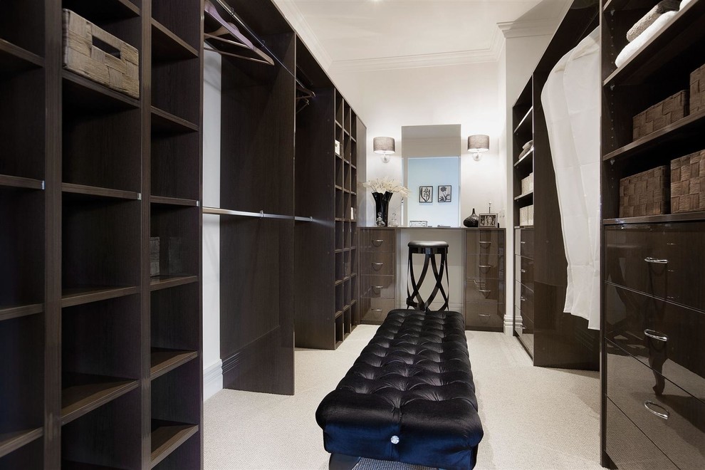 Photo of a large traditional gender-neutral walk-in wardrobe in Melbourne with flat-panel cabinets, dark wood cabinets and carpet.
