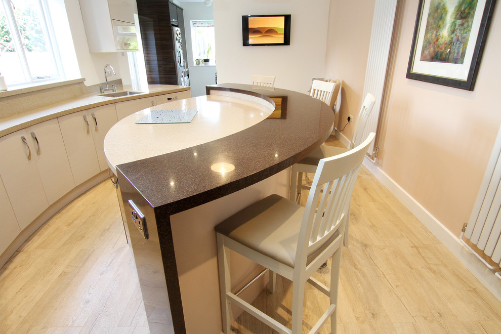 This is an example of a large modern eat-in kitchen in Hampshire with an undermount sink, flat-panel cabinets, solid surface benchtops, beige splashback, stainless steel appliances, plywood floors and with island.