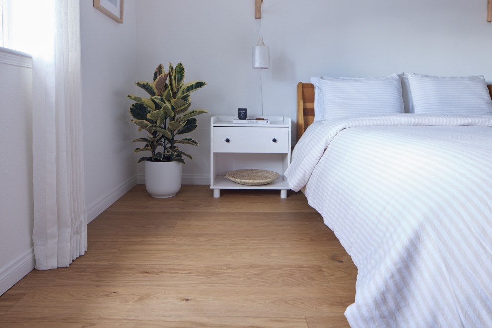 Immagine di una camera matrimoniale minimalista di medie dimensioni con pareti bianche, parquet chiaro e pavimento marrone