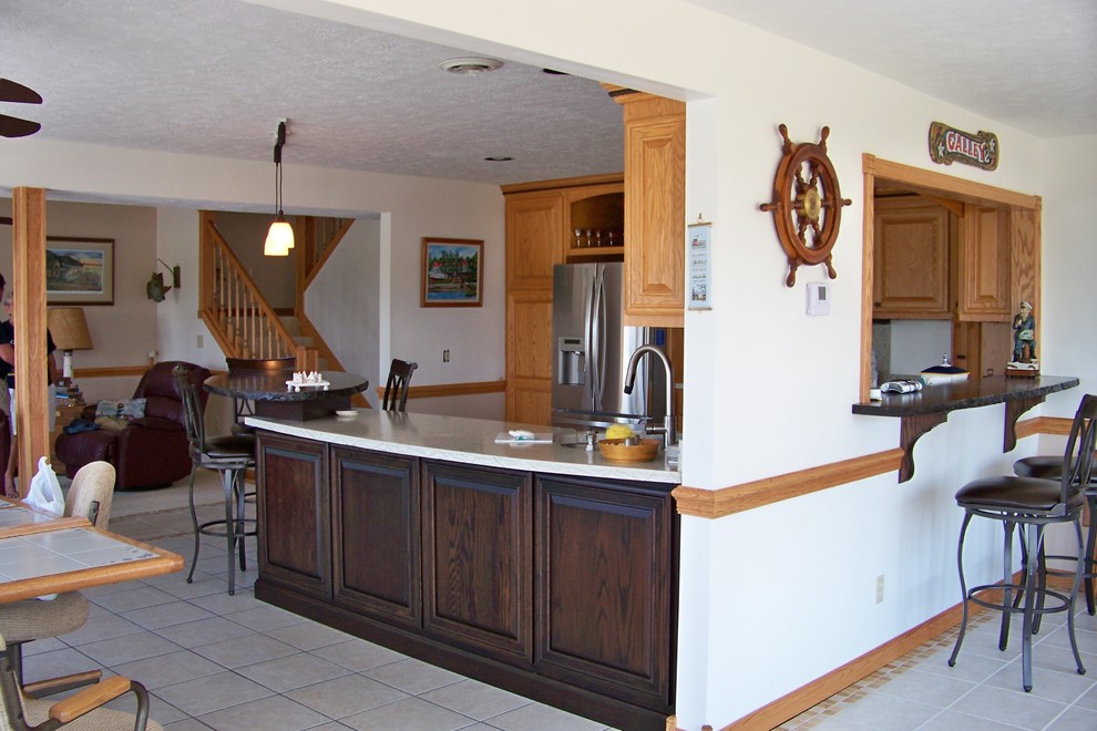 Kitchen - medium tone wood floor kitchen idea with a double-bowl sink, medium tone wood cabinets, granite countertops, beige backsplash and stainless steel appliances