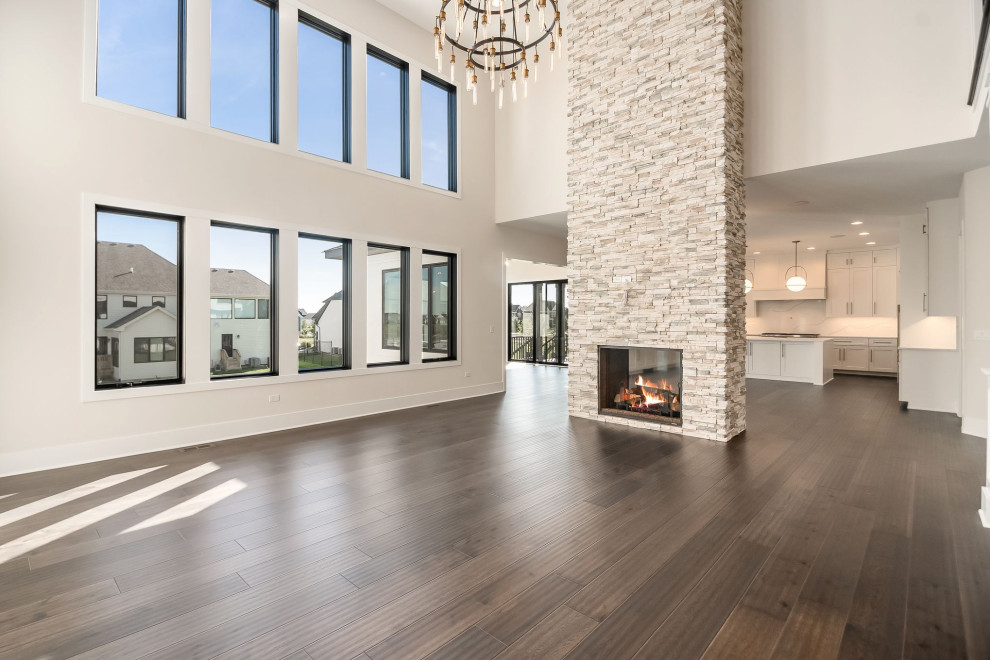 Design ideas for a large open concept family room in Chicago with beige walls, dark hardwood floors, a two-sided fireplace, a wall-mounted tv and brown floor.