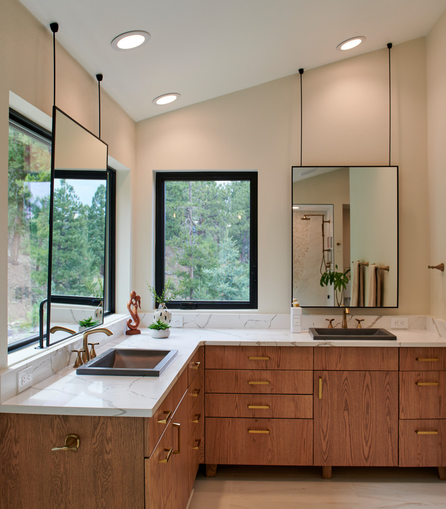 Design ideas for a transitional bathroom in Denver with flat-panel cabinets, medium wood cabinets, beige walls, a drop-in sink, beige floor, white benchtops, a double vanity, a built-in vanity and vaulted.