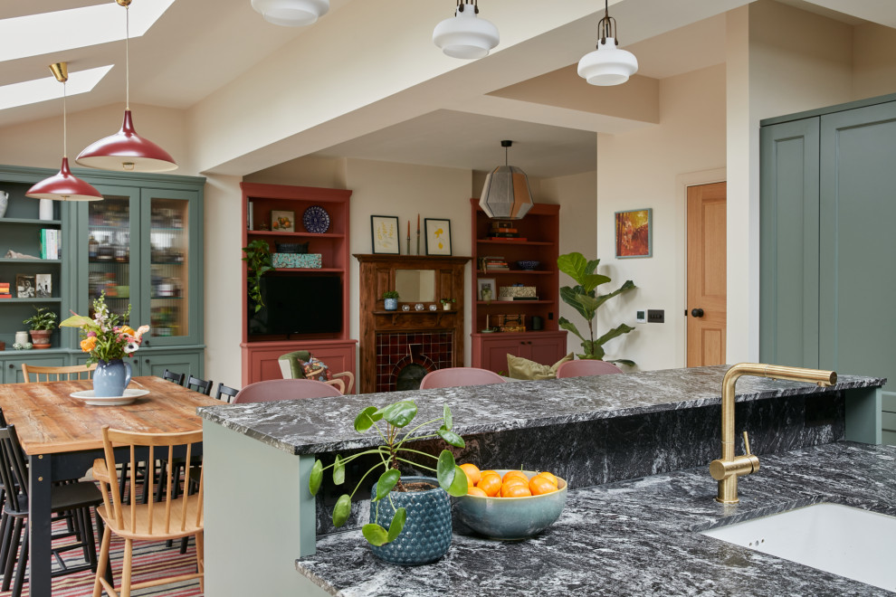 Пример оригинального дизайна: угловая кухня-гостиная среднего размера в классическом стиле с с полувстраиваемой мойкой (с передним бортиком), фасадами с утопленной филенкой, зелеными фасадами, гранитной столешницей, черным фартуком, фартуком из гранита, светлым паркетным полом, островом, черной столешницей и сводчатым потолком