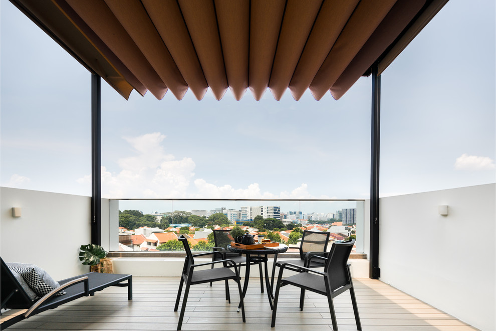 Inspiration for a contemporary balcony in Singapore with an awning and glass railing.