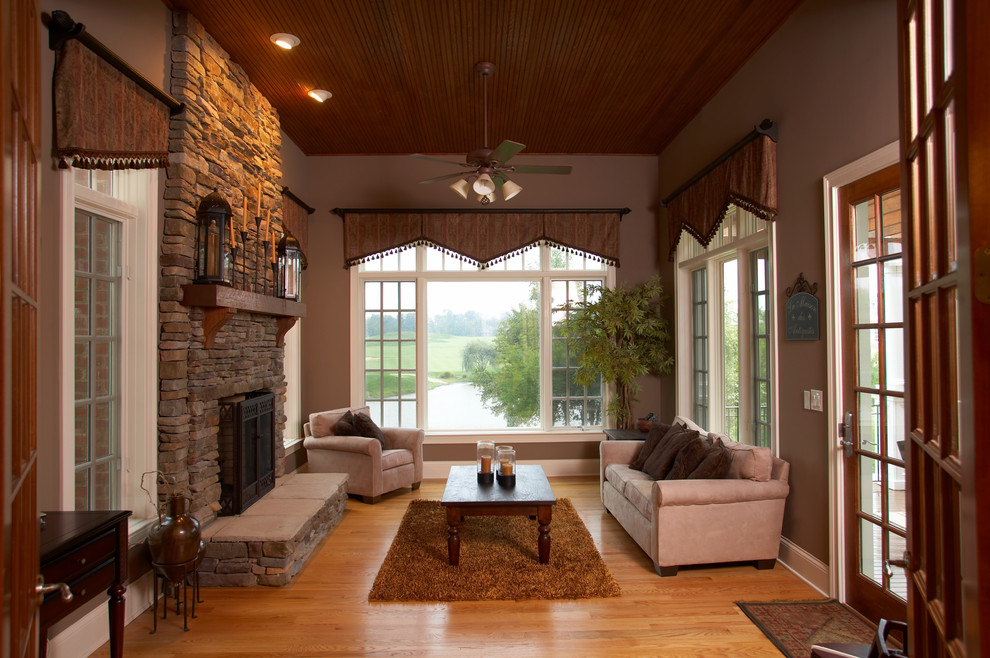 Photo of a mid-sized traditional formal enclosed living room in Columbus with brown walls, medium hardwood floors, a standard fireplace, a stone fireplace surround and no tv.