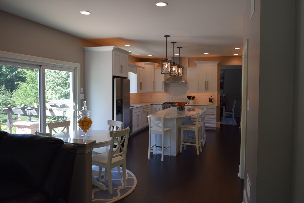 Example of a huge transitional l-shaped dark wood floor eat-in kitchen design with an undermount sink, shaker cabinets, white cabinets, quartz countertops, white backsplash, subway tile backsplash, stainless steel appliances and an island