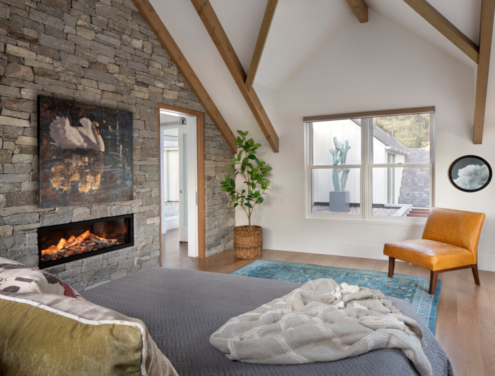 Modernes Hauptschlafzimmer mit braunem Holzboden, Gaskamin, Kaminumrandung aus Stein und freigelegten Dachbalken in Sonstige