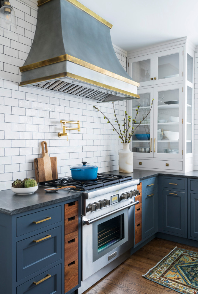 Inspiration for a mid-sized transitional u-shaped kitchen in New York with a single-bowl sink, shaker cabinets, blue cabinets, granite benchtops, white splashback, ceramic splashback, panelled appliances, medium hardwood floors, with island, brown floor and black benchtop.