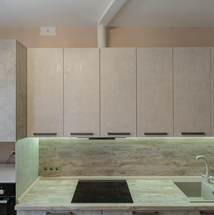 Industriell inredning av ett mellanstort brun brunt kök, med en nedsänkt diskho, luckor med infälld panel, vita skåp, träbänkskiva, brunt stänkskydd, stänkskydd i trä, integrerade vitvaror, mellanmörkt trägolv och beiget golv