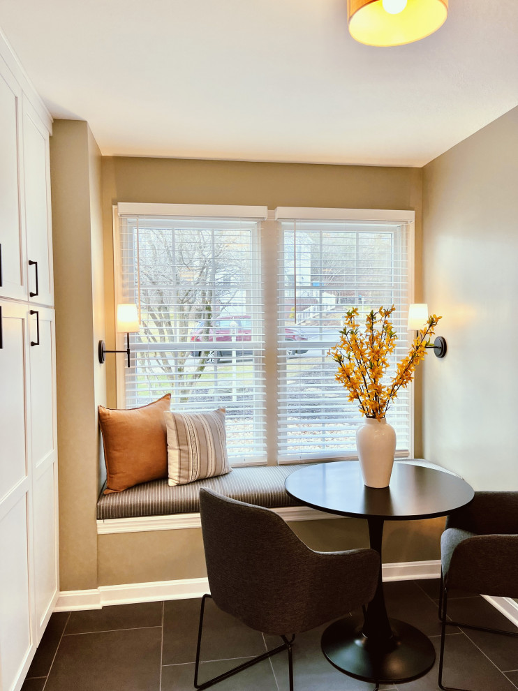 Example of a mid-sized transitional l-shaped vinyl floor and black floor eat-in kitchen design with a farmhouse sink, shaker cabinets, white cabinets, quartz countertops, gray backsplash, ceramic backsplash, stainless steel appliances, a peninsula and gray countertops