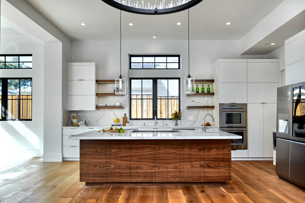 Foto på ett stort funkis vit linjärt kök och matrum, med en undermonterad diskho, släta luckor, vita skåp, bänkskiva i kvarts, vitt stänkskydd, stänkskydd i sten, rostfria vitvaror, mellanmörkt trägolv och en köksö