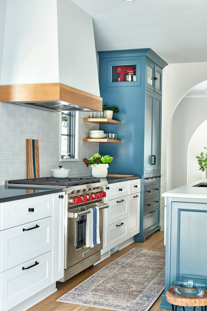 Klassisk inredning av ett linjärt kök, med blå skåp, rostfria vitvaror och flera köksöar