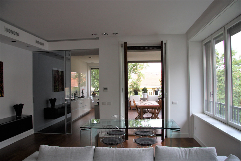 Large midcentury formal enclosed living room in Milan with white walls, dark hardwood floors, brown floor and recessed.