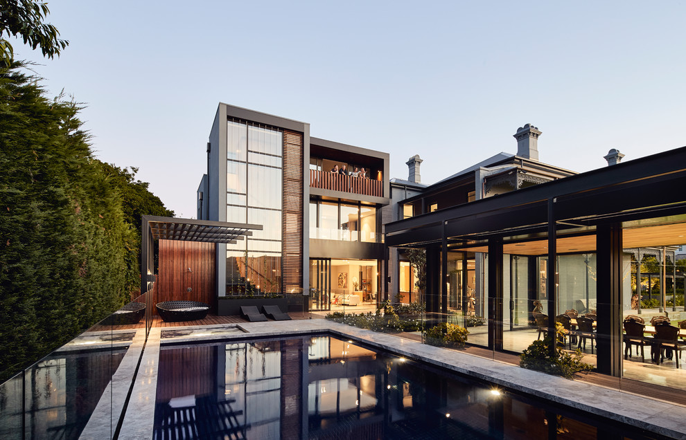 Large contemporary backyard rectangular aboveground pool in Melbourne with a pool house and natural stone pavers.