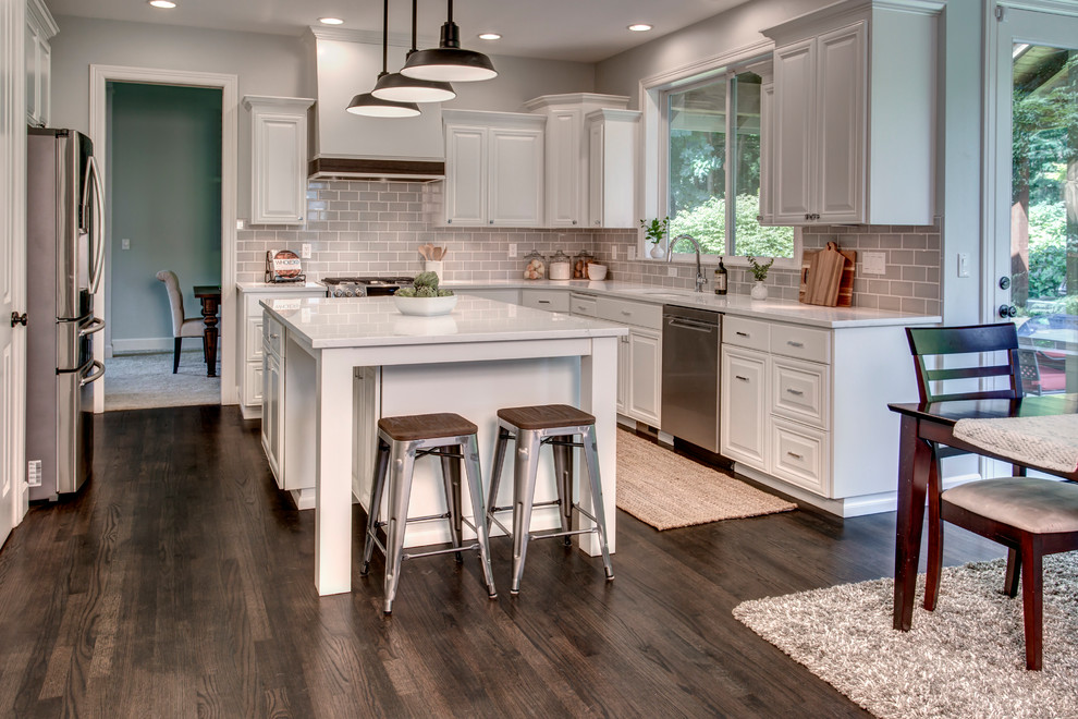 Eat-in kitchen - large transitional u-shaped dark wood floor and brown floor eat-in kitchen idea in Seattle with an undermount sink, raised-panel cabinets, white cabinets, marble countertops, gray backsplash, ceramic backsplash, stainless steel appliances and an island