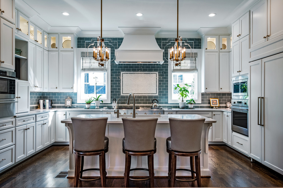 Large transitional u-shaped dark wood floor and brown floor kitchen photo with shaker cabinets, white cabinets, an island, an undermount sink, marble countertops, blue backsplash, subway tile backsplash and stainless steel appliances
