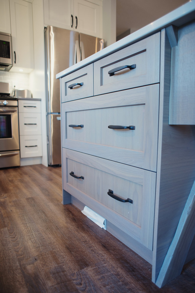Inspiration for a mid-sized transitional l-shaped brown floor open concept kitchen remodel in Vancouver with shaker cabinets, white cabinets, quartz countertops, gray backsplash, stainless steel appliances and an island