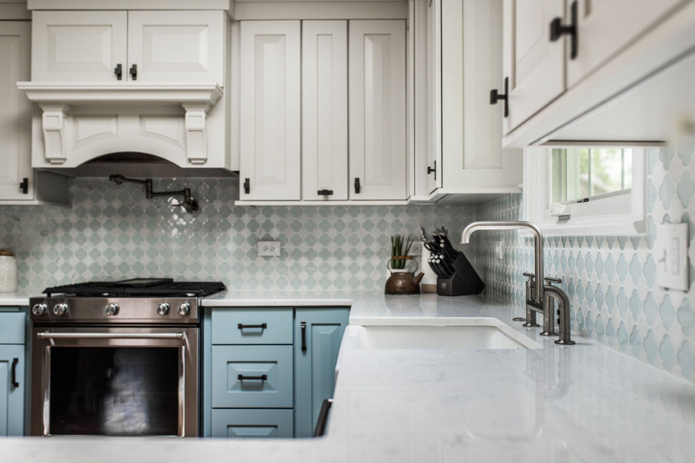 Eat-in kitchen - mid-sized transitional u-shaped medium tone wood floor and brown floor eat-in kitchen idea in Chicago with a farmhouse sink, raised-panel cabinets, blue cabinets, quartz countertops, white backsplash, glass tile backsplash, stainless steel appliances, no island and white countertops