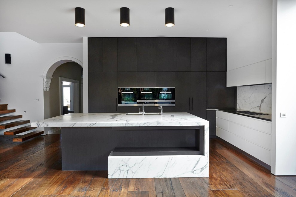 Photo of a large contemporary l-shaped eat-in kitchen in Melbourne with an undermount sink, flat-panel cabinets, marble benchtops, stone slab splashback, stainless steel appliances, dark hardwood floors and with island.