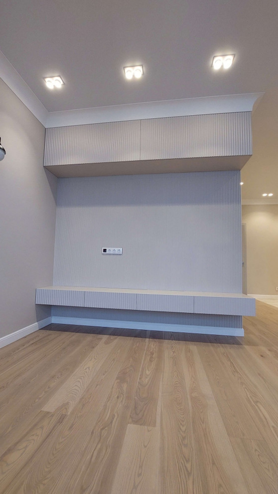 Источник вдохновения для домашнего уюта: изолированная гостиная комната среднего размера в стиле модернизм с бежевыми стенами, паркетным полом среднего тона, телевизором на стене, бежевым полом, обоями на стенах и синим диваном